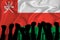 Silhouette of raised arms and clenched fists on the background of the flag of Oman. The concept of power,  conflict. With place