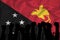 Silhouette of raised arms and clenched fists on the background of the flag of Papua New Guinea. The concept of power,  conflict.