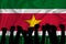 Silhouette of raised arms and clenched fists on the background of the flag of suriname. The concept of power,  conflict. With