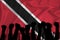 Silhouette of raised arms and clenched fists on the background of the flag of Trinidad and Tobago. The concept of power,  conflict