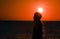 Silhouette of Rastafari man against glowing sun during sunset over the ocean