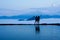 Silhouette rear view of young woman standing near the pool for amazing landscape of blue sky and mountains in morning fog.