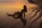 Silhouette and reflection of girl sitting on surfboard at ocean beach on background of beautiful sunset