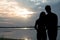 The silhouette of a romantic couple standing, hugging each other and watching the sunset. Romance and love concept