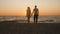 Silhouette of a romantic young couple standing on the seashore, man comes up and takes the girl`s hand and together enjoying sunri