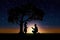 Silhouette of a romantic young couple under a tree in the rays of the sunset in the evening of summer