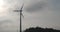 Silhouette of rotating blades of a windmill propeller on gray sky background. Wind power generation. Pure green energy.