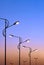 Silhouette row of modern street lampposts against colorful dramatic sky background