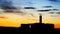 Silhouette of ruin of abandoned house with large chimney in front of intense colored sunset