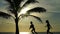 Silhouette of running children against the background of the ocean and palm trees.