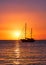 Silhouette of sailing boat with sails down against sun at sunset, sun glare on sea waters. Romantic seascape. Lifestyle