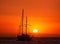 Silhouette of sailing boat with sails down against sun at sunset, sun glare on sea waters. Romantic seascape. Sailboat