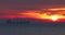 Silhouette of sailing industrial cargo ship with containers in the sea against burning sunrise sky with dramatic clouds