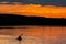 Silhouette of a sailor in a kayak canoe on the lake in the sunset light near an island