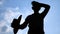 Silhouette of Senior Asian farmer took off a hat and wiped off the sweat on his face after work on sky background