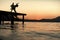 Silhouette of sensual couple dancing on pier with sunset above sea surface on background. Romance and love concept