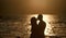 Silhouette of sensual couple kissing with sunset above sea surface on background. Couple in love on romantic date in