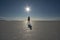 Silhouette and shadow of a person in bright sunshine and blue sky in the vastness of the dry Salt Flats of Uyuni, Bolivia
