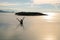 Silhouette shot of Asian women raise hand and enjoy vacation inside infinite pool with ocean sunset view and island at the