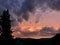 Silhouette shot of a tree and a hill on a fiery indigo sunset sky