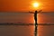 Silhouette of single Asian girl enjoying herself during sunset on the beach red sky