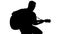 Silhouette of sitting man playing the guitar on a