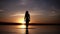 Silhouette of a slender girl walking on the water do the stains on the surface. Incredible sunset in the background