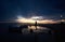 Silhouette of slim girl standing on narrow wooden bridge at small motor boats at sunset