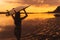 Silhouette of slim girl with surfboard in hands at beach on background of beautiful sunset