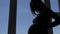 Silhouette Of Slim Pregnant Woman Stroking Her Stomach Standing Near Window