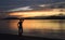 Silhouette of a slim woman on the bright tropical sunset background , sea and mountains on the horizon, the small island  Gili Asa