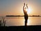 Silhouette of slim woman with hands up in the air illuminated with sunshine dancing traditional tribal belly dance