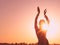 Silhouette of slim woman with hands up in the air illuminated with sunshine dancing traditional tribal belly dance in front of aur