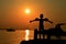 Silhouette of small boy spreading hands with swimming sleeves on arms towards sunset on molo in Croatia, Adriatic