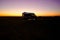 Silhouette of a small camper parked in a beautiful open landscape at sunset