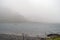 Silhouette of a small fishing motor boat in a lake, Huge mountain covered with fog in the background. Connemara, Ireland