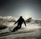 A silhouette of a snowboarder going down the slope in the opposing light