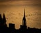 A silhouette of the spinnaker tower in portsmouth with a flock of birds flying past