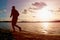 Silhouette of sport active man running on evening beach water mountain and sunset cloudy sky background.