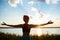 Silhouette of sportive girl practicing yoga in field at sunrise.