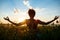 Silhouette of sportive girl practicing yoga in field at sunrise.