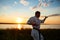 Silhouette of sportive man training karate in field at sunrise.