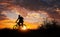 Silhouette of sports person cycling on the meadow on the beautiful sunset.