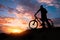 Silhouette of sports person cycling on the meadow on the beautiful sunset.