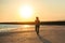 silhouette of sportswoman with smartphone in running armband case jogging on beach against