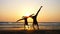 Silhouette of sporty young women practicing acrobatic element on the beach.