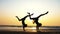 Silhouette of sporty young women practicing acrobatic element on the beach.