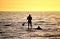 Silhouette of Stand up paddler at sunset, paddle board sport.