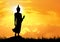 silhouette standing Buddha with sunlight on sky background