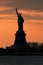 Silhouette of Statue of Liberty against a vivid orange sunset sky concept for NYC landmarks, American patriotism and symbol of fre